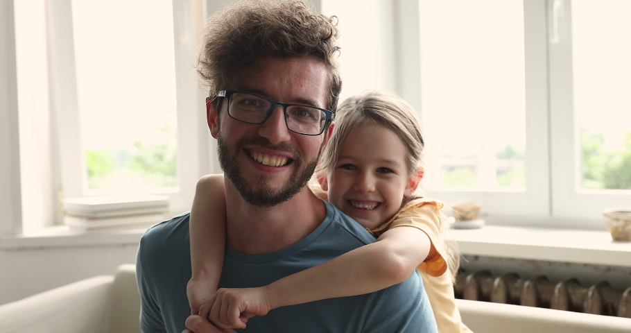 Close up portrait of happy young father and his little, cute daughter. Preschool girl piggy back his loving daddy, cheerful attractive family smile looking at camera. Bonding, fatherhood, bond concept Royalty-Free Stock Footage #1085422418