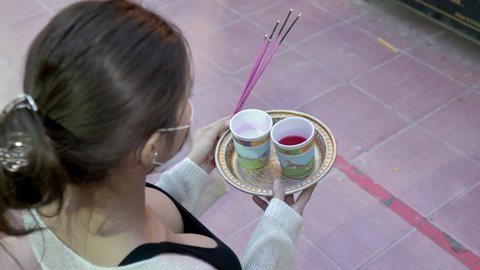 Single young woman praying worship to Ganesh God offering cups with white and red colored water to pray for love and luck at Ganesh temple, Huai Khwang. 10bit, 422. Bangkok, Thailand Nov 15 2021
