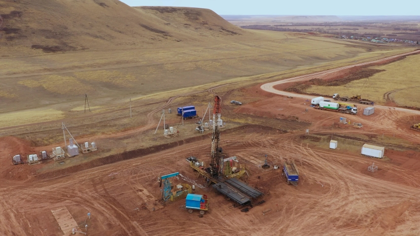 Oil field development. A drilling rig among the hills on a cloudy autumn day.