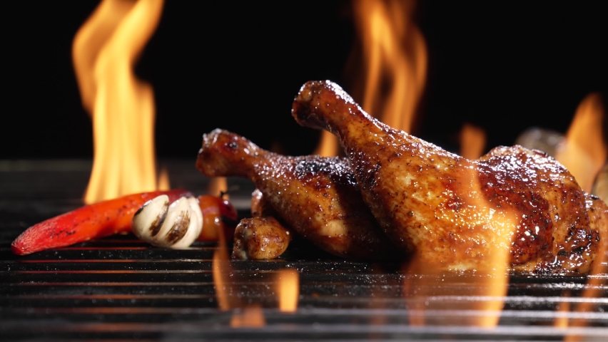 Chicken thighs grilled on hot barbecue charcoal flaming grill with sauce brushed on top. Juicy chicken meat roasted on bbq grill. slow motion | Shutterstock HD Video #1085428163