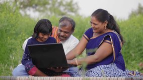 Happy progressive farmer family sitting outdoors on the farm including father, mother, and daughter using a laptop and interacting with each other. Concept of rural Family, relationship and farming - Powered by Shutterstock - Get 15% off with code: PIKWIZARD15
