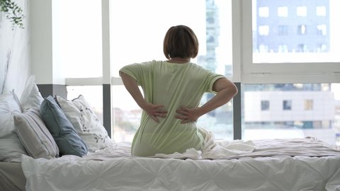 Back pain, woman with backache in the bedroom, health problems concept