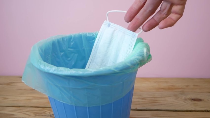 Hand throwing medical mask away, trash bin with used mask inside, medecine in trashcan, pharmaceutical waste, expired medicines