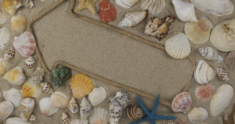 Arrow made of rope lying on the sand with space for design, space for text. Rotation of the pointer among shells and starfish. Top view