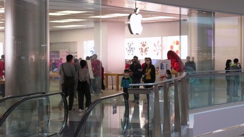 Hong Kong , Kowloon , China - 01 09 2022: People walk past the multinational American technology brand official Apple store and logo at a shopping mall in Hong Kong.