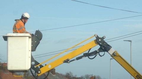 St Helens , United Kingdom (UK) - 01 08 2022: Telecom technician working repairing telephone pole power cable in boom crane basket descending