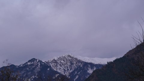 4K Time-lapse of the snow covered mountain during the morning at Manali in Himachal Pradesh, India. Early morning yellow light hits the peak of the snow covered Himalayan mountain turning it orange.  