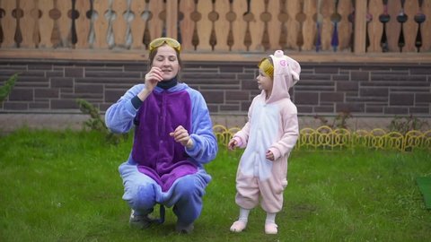 crazy dance girl and woman in kigurumi pajamas. Two sisters have fun. lovely mom, dancing, relaxing clothes, cosplay, pajamas, daughter. Close-up family enjoy music and party on front lawn. outdoor