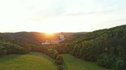 Aerial drone view of magic sunset over the Karlstejn castle, Czech republic. Famous castle is built on top of hill in the forest. Summer weather, soft and warm light.