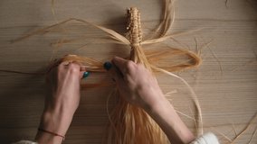 a girl weaves macrame in the form of a large Bali leaf from the bark of a young lime tree in a bright room. women's hands weave macrame. macrame in the video of a large sheet hanging on the wall