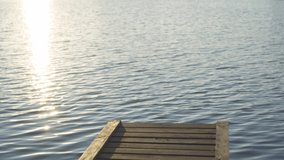 Close-up view 4k stock video footage of brown organic wooden pier isolaetd on blue sunny sunset river water surface