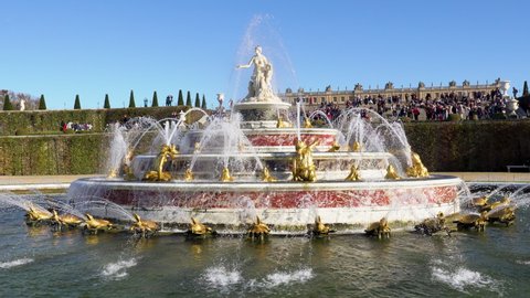 Versailles, France - October 24, 2021: The Latona Fountain in the Gardens of Versailles with the castle the background. Unidentified visitors in the background.