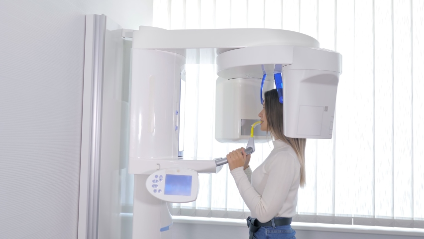 Scanning of the dental jaw. A patient undergoing the procedure of panoramic radiography of the oral cavity using an orthopantomographic device in modern dentistry, Diagnostic equipment Royalty-Free Stock Footage #1085457524
