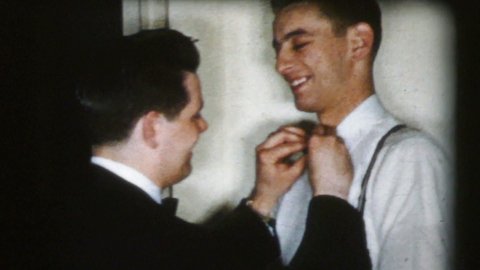 TRENTON, NEW JERSEY, MARCH, 1960: A best man carefully fixes the bow tie of a handsome nervous young groom before his big wedding day in 1960. 
