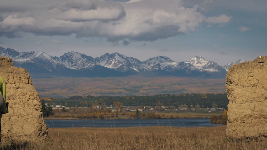 The man and woman travel on mixed terrain cycle touring with bikepacking. The two people journey with bicycle bags. Mountain snow capped, stone arch.