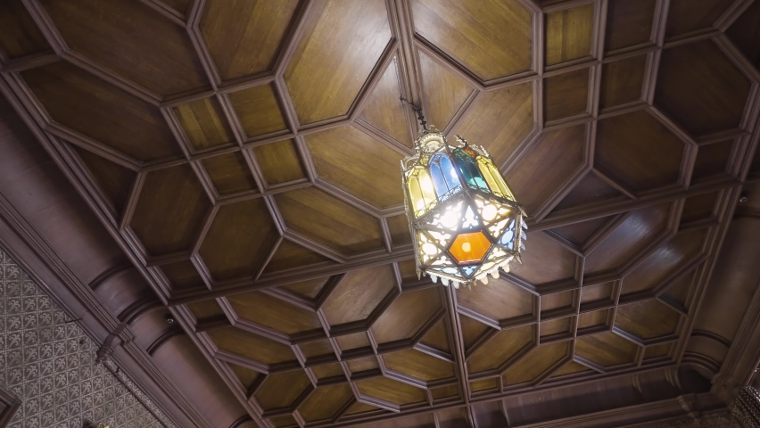 Bottom view of a wooden beautiful old fashioned ceiling with a hanging chandelier made of stained glass. Action. Details of a retro stylized room or a museum.