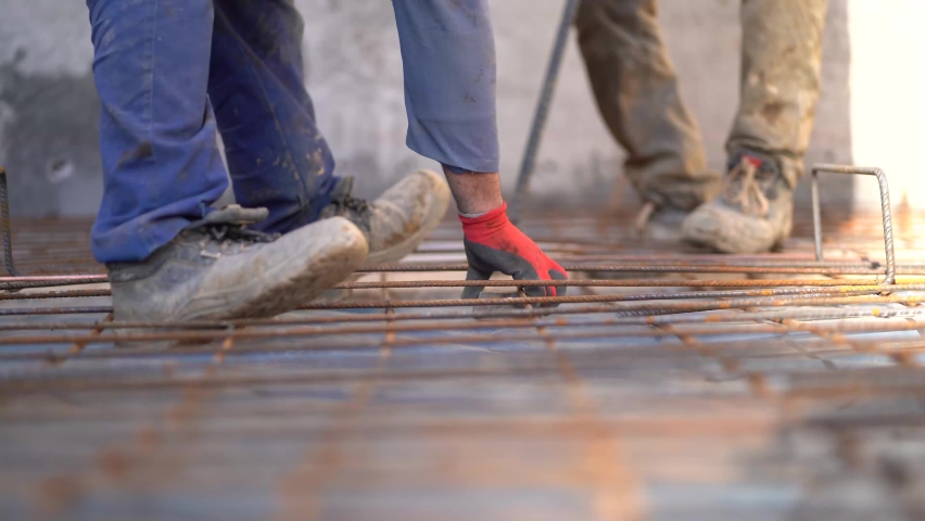 Workers adjusting rusty metal wiring laid on the ground of a house under construction. Reinforced basement floor, close up static 4K
 Royalty-Free Stock Footage #1085466974