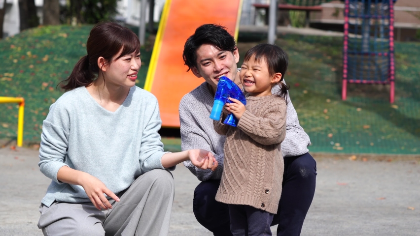Asian parents and their daughter playing at the park