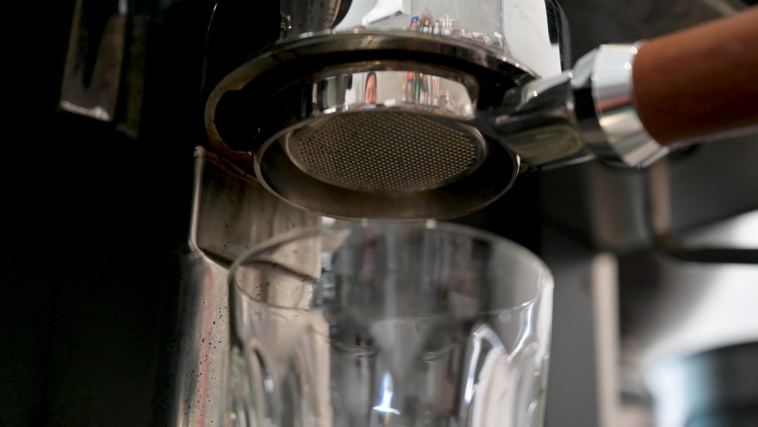 Pouring coffee stream from professional machine in cup. Barista man making espresso shot by bottomless, using filter holder. Flowing fresh ground coffee. Drinking roasted black coffee in the morning Royalty-Free Stock Footage #1085470010