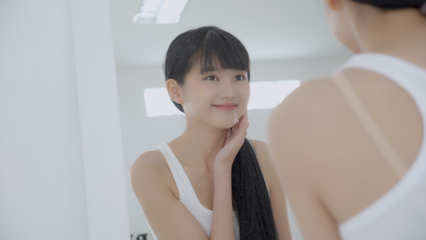 Beautiful face of young asian woman with happy smiling and touch cheek looking mirror with charming, makeup of beauty facial girl with skincare and cosmetic treatment, skin care and healthy concept. | Shutterstock HD Video #1085470070