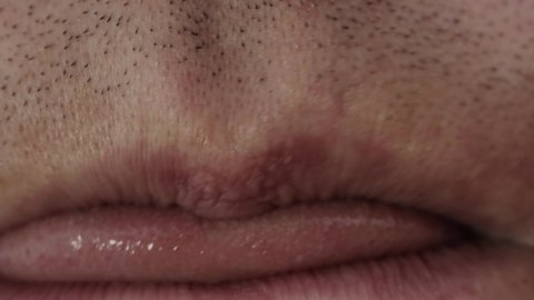 The man nervously licks his lips with his tongue, macro