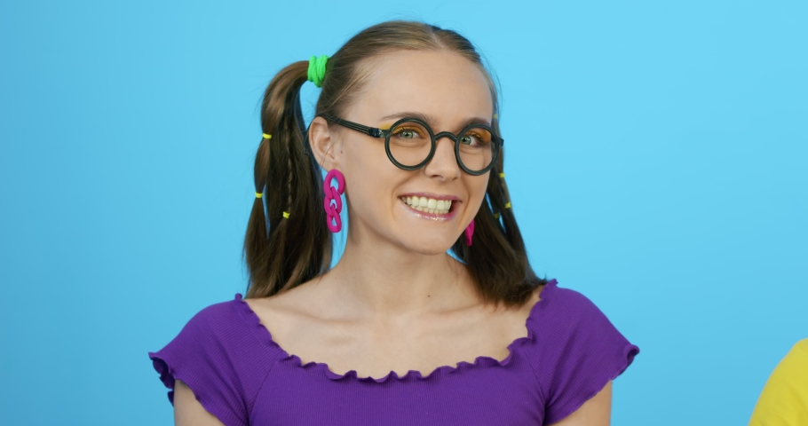Portrait of a cheerful girl with glasses smiling. A cute schoolgirl is sitting at a table at school.