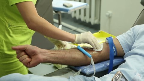 Yerevan, Armenia - September, 2021: Take blood from volunteers at donor center. The nurse puts a tourniquet on arm, pricks needle into patients arm. Transfusion Machine Collects Blood Plasma