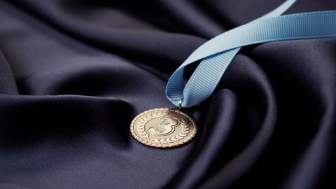 Bronze medal with ribbon on black background close-up. The third place. Award and victory, winning the championship. 