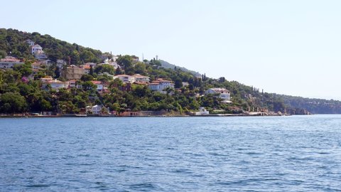 View of Buyukada Island from moving boat, expensive mansions and ruins of Trotsky House visible on shore. Famous Adalar at summer time, landmark and tourist attraction of Istanbul visitors