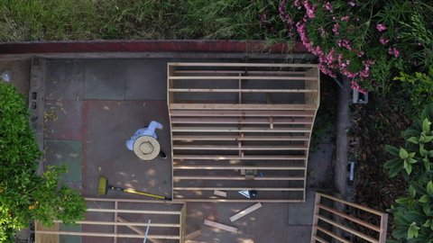 Group of men working and constructing homemade mini ramp in backyard, aerial top down view