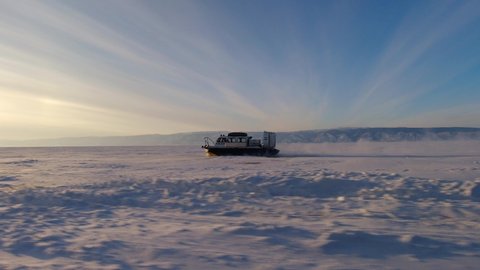 Khuzhir, Russia- March 1, 2021: Hovercraft driving at high speed on snow covered frozen ice surface of Lake Baikal at dusk.