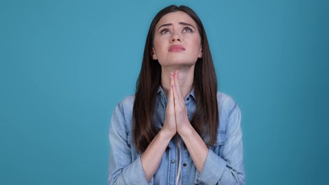Nervous upset lady look up pray isolated blue color background