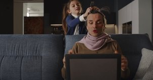 Funny Family Situation: Portrait of a Man Having a Video Call Conference with his Colleagues Using Laptop Computer at Home While his Daughter is Playing Makeup on him. Work from Home Concept