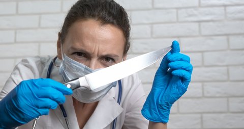Doctor with a knife. A doctor in uniform try to scare with her big knife for work.