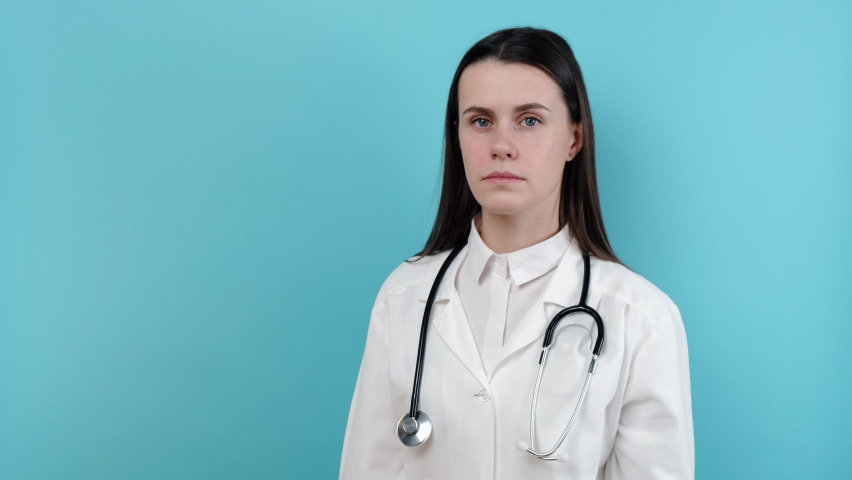 Portrait of upset young female doctor feeling tension, guilt blaming herself for professional mistake. Depressed worried woman therapist thinking of mental fatigue, isolated on blue studio background Royalty-Free Stock Footage #1085497913