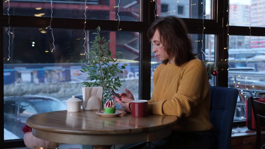 The girl sits in a cafe and takes a selfie on the phone