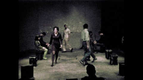 1960s: People perform in small theater. Man runs. People yell.
