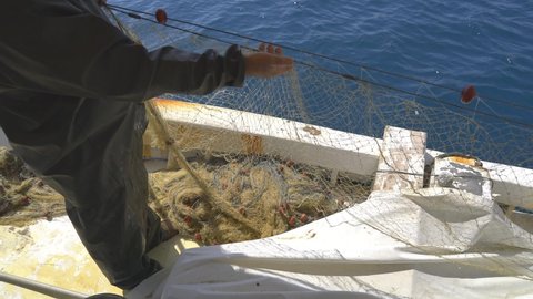 Fishing nets gather on the boat.A fisherman collects nets.Nylon net with float line attached to plastic floats.Collecting fishing net.Nets are devices made from fibers woven in a grid-like structure.