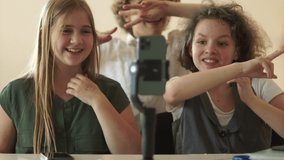 Teenagers laugh and dance in front of the camera of a smartphone located on a tripod. Schoolchildren Shoot Video Trends for Social Media