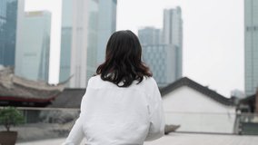 pretty young asian woman in white shirt running in the urban city square enjoy the view exciting travel tour concept at Chengdu China 4k slow motion clip camera follow view