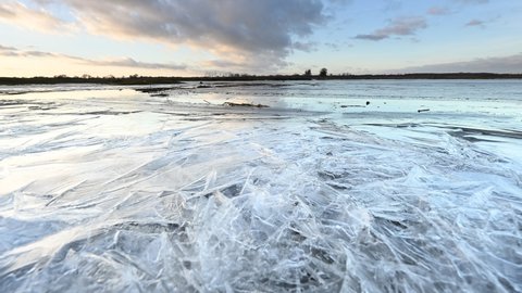 Partly frozen river in winter, sunset