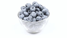 Blueberries in a glass bowl on a white background. Side view. Loop motion. Rotation 360. 4K UHD video footage 3840X2160.