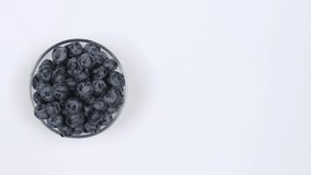 Blueberries in a glass bowl on a white background. Top view. Loop motion. Free space on the right. Rotation 360. 4K UHD video footage 3840X2160.
