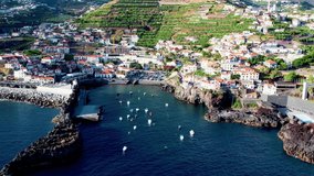 Aerial 4K footage of drone flight over Camara de Lobos fisherman village in Madeira Island with a bay with many small boats