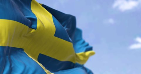Detail of the national flag of Sweden waving in the wind on a clear day. Democracy and politics. North European country. Selective focus. Seamless Slow motion