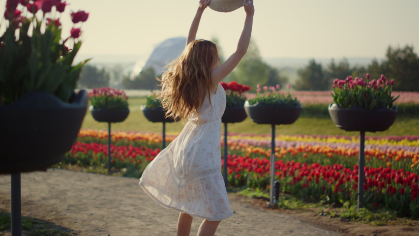 Happy woman dancing in beautiful summer park outdoors. Pretty girl jumping with lightness and elegance in spring flower garden outside. Smiling lady feeling happiness and joy in yard in bloom outdoor. Royalty-Free Stock Footage #1085515472