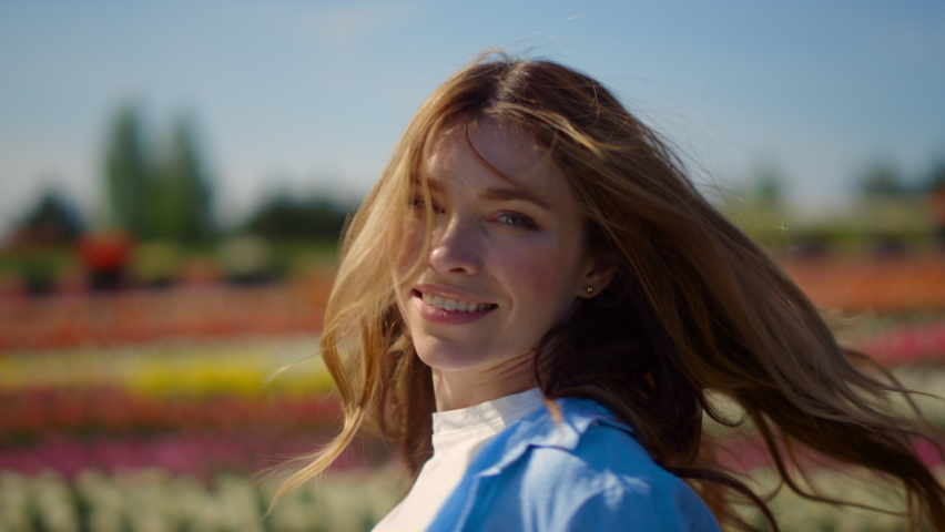 Portrait of smiling woman dancing in flower field outdoors. Flirty girl with long red hair turning around in spring park. Closeup young female person feeling free in blooming garden in summer day. Royalty-Free Stock Footage #1085515565