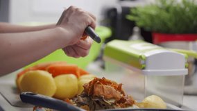Woman cooking in the kitchen, female hands peeling boiled carrot with knife on kitchen countertop closeup. High quality 4k footage