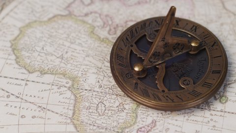An atique brass sundial navigational instrument on a vintage world map