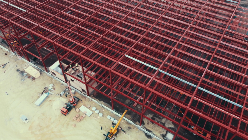 Construction of warehouse from metal structures. Industrial building on light gauge steel framing. Frame of modern hangar or factory. Aerial view of a construction site with steel structure warehouse Royalty-Free Stock Footage #1085521283
